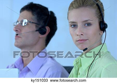 Stock Image - Young businessman and businesswoman wearing headset. Fotosearch