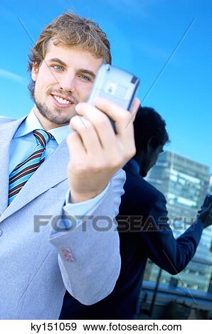 Young businessman holding mobile phone View Large Photo Image Stock Photo - Young businessman holding mobile phone. Fotosearch