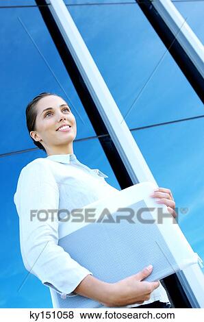 Young businesswoman standing by office building, low angle view View Large Photo Image Stock Photo - Young businesswoman standing by office building, low angle view. Fotosearch