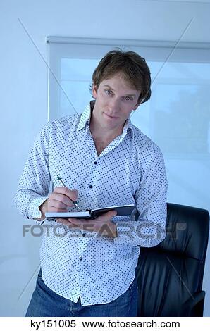 Stock Photography - Young man writing on notebook, portrait. Fotosearch