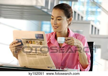Businesswoman holding cup and reading newspaper in office View Large Photo Image Stock Image - Businesswoman holding cup and reading newspaper in office. Fotosearch