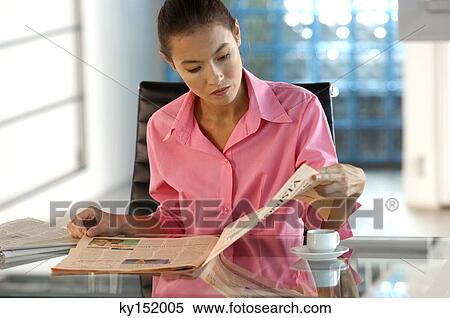 Businesswoman reading newspaper in office View Large Photo Image Stock Photography - Businesswoman reading newspaper in office. Fotosearch