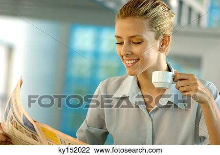 Stock Image - Businesswoman reading newspaper, smiling. Fotosearch
