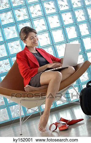 Stock Image - Businesswoman using laptop, smiling. Fotosearch