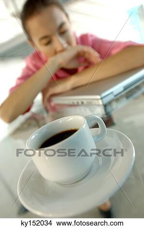 Cup of black coffee on glass tabletop with young woman in background View Large Photo Image Picture - Cup of black coffee on glass tabletop with young woman in background. Fotosearch