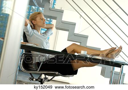 Young businesswoman resting in office with legs on desk View Large Photo Image Stock Photo - Young businesswoman resting in office with legs on desk. Fotosearch