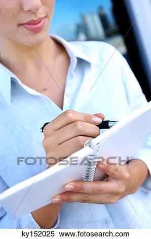 Stock Photography - Young woman writing on notebook. Fotosearch