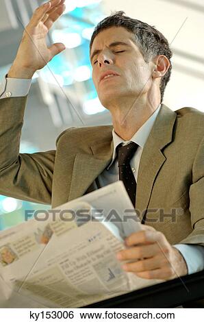 Businessman sitting by table, holding newspaper View Large Photo Image Stock Photograph - Businessman sitting by table, holding newspaper. Fotosearch