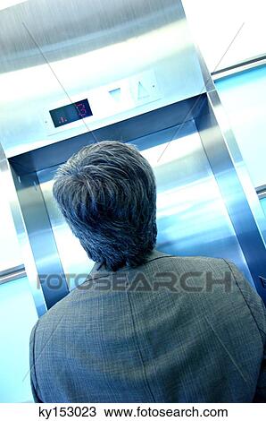 Businessman waiting by elevator, rear view View Large Photo Image Stock Image - Businessman waiting by elevator, rear view. Fotosearch