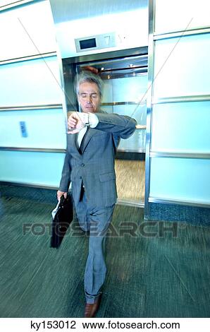 Mature businessman looking at wristwatch View Large Photo Image Stock Image - Mature businessman looking at wristwatch. Fotosearch