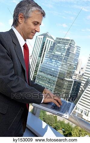 Mature businessman using laptop in balcony View Large Photo Image Stock Photo - Mature businessman using laptop in balcony. Fotosearch