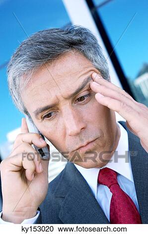 Stock Image - Mature businessman using mobile phone, close-up. Fotosearch