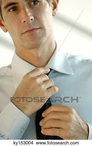 Picture - Young businessman adjusting tie. Fotosearch