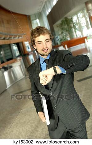 Stock Image - Young businessman looking at wristwatch. Fotosearch