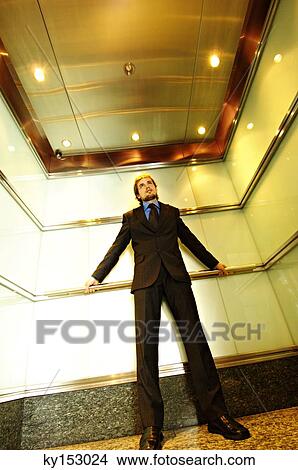 Young businessman standing in elevator, low angle view View Large Photo Image Picture - Young businessman standing in elevator, low angle view. Fotosearch