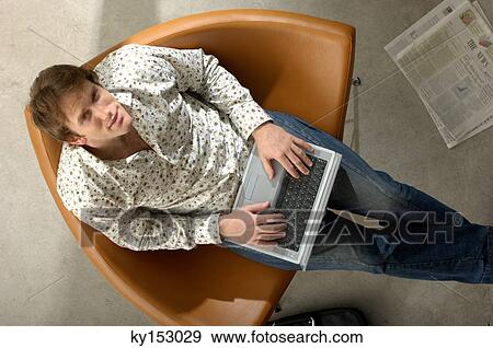 Stock Photo - Young businessman using laptop, portrait, high angle view. Fotosearch