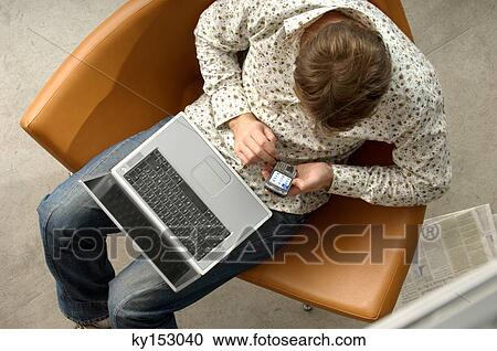 Young businessman using mobile phone and laptop, overhead view View Large Photo Image Stock Image - Young businessman using mobile phone and laptop, overhead view. Fotosearch