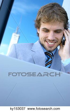 Young businessman using mobile phone and laptop, close-up View Large Photo Image Stock Photo - Young businessman using mobile phone and laptop, close-up. Fotosearch