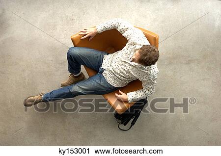 Young man relaxing on chair, overhead view View Large Photo Image Stock Image - Young man relaxing on chair, overhead view. Fotosearch