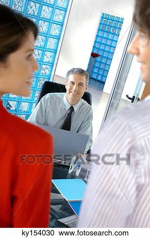Stock Image - Business people smiling in office. Fotosearch