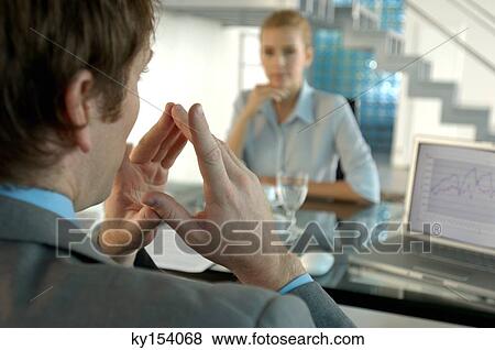 Stock Photo - Businessman conversing with businesswoman in background. Fotosearch