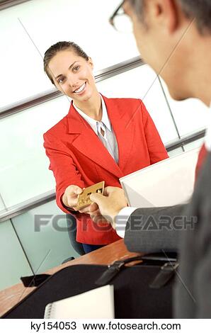 Stock Image - Businessman handing credit card to businesswoman in office. Fotosearch