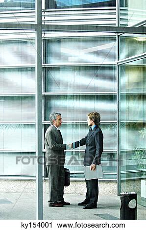 Businessmen shaking hands by office building View Large Photo Image Stock Image - Businessmen shaking hands by office building. Fotosearch