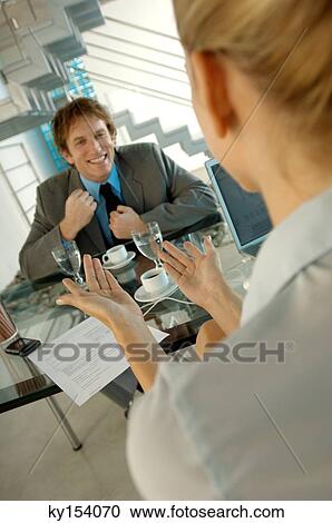 Stock Image - Businesswoman conversing with man in office. Fotosearch