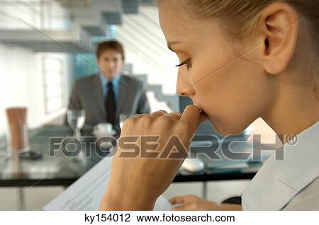 Stock Image - Businesswoman in office with colleague in background. Fotosearch