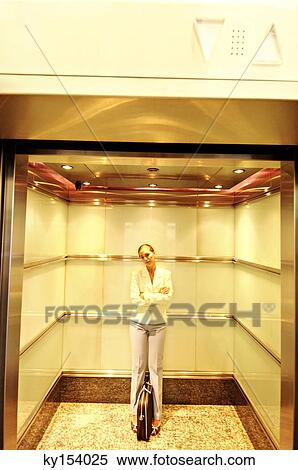 Businesswoman standing in elevator with folded arms View Large Photo Image Stock Photography - Businesswoman standing in elevator with folded arms. Fotosearch