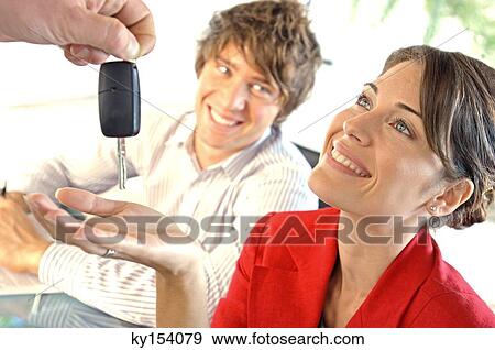 Stock Photo - Car dealer handing car key to customer, smiling. Fotosearch