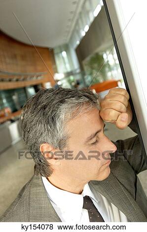 Stock Photo - Mature businessman leaning on wall. Fotosearch