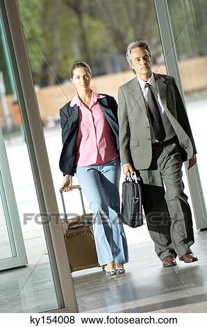 Mature man and young woman walking with suitcase at corridor View Large Photo Image Stock Photo - Mature man and young woman walking with suitcase at corridor. Fotosearch