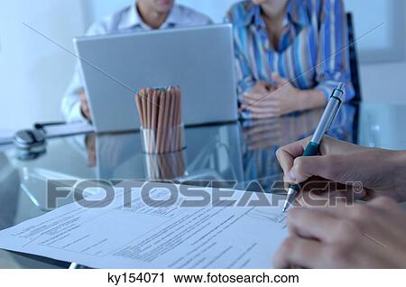 Stock Image - Person signing on document, close-up. Fotosearch