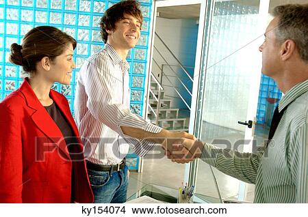 Picture - Two businessmen shaking hands, smiling. Fotosearch