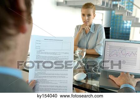 Stock Image - Young woman sitting in office. Fotosearch