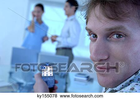 Stock Photo - Businessman holding mobile phone, portrait. Fotosearch