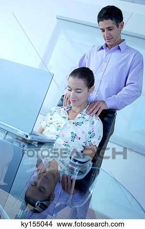 Picture - Businessman massaging businesswoman, smiling. Fotosearch