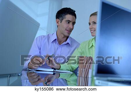 Businessman sitting with female colleague in office, smiling View Large Photo Image Stock Photograph - Businessman sitting with female colleague in office, smiling. Fotosearch