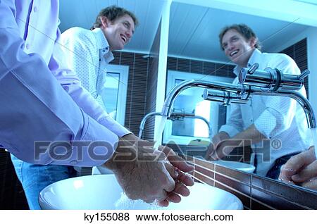 Stock Photo - Businessmen washing hands in washroom, smiling. Fotosearch