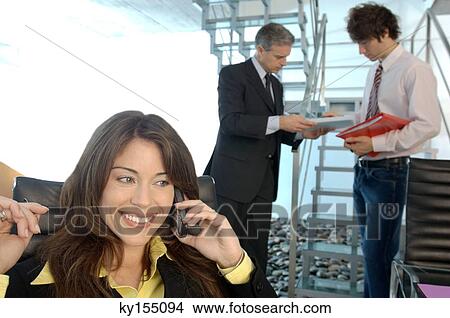 Businesswoman using mobile phone with colleagues in background View Large Photo Image Picture - Businesswoman using mobile phone with colleagues in background. Fotosearch