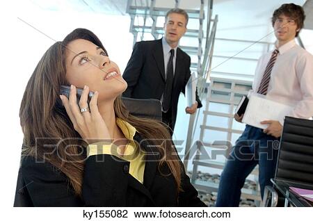 Businesswoman using mobile phone with colleagues in background View Large Photo Image Stock Image - Businesswoman using mobile phone with colleagues in background. Fotosearch