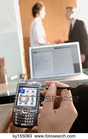 Businesswoman using mobile phone with colleagues in background View Large Photo Image Stock Image - Businesswoman using mobile phone with colleagues in background. Fotosearch