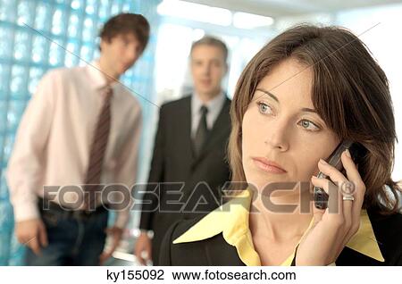 Businesswoman using mobile phone with colleagues in background View Large Photo Image Stock Image - Businesswoman using mobile phone with colleagues in background. Fotosearch