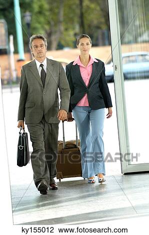 Stock Image - Mature man and young woman walking in corridor. Fotosearch