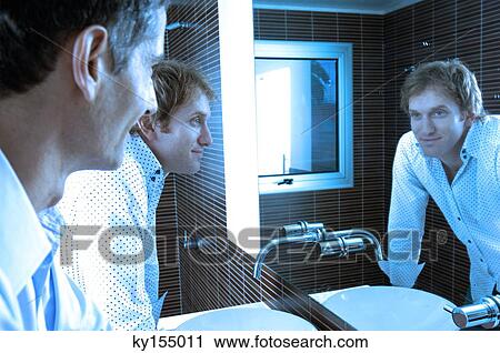 Men looking at mirror in washroom, smiling View Large Photo Image Stock Image - Men looking at mirror in washroom, smiling. Fotosearch