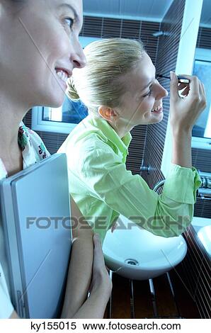 Young women looking at mirror in washroom View Large Photo Image Stock Photography - Young women looking at mirror in washroom. Fotosearch