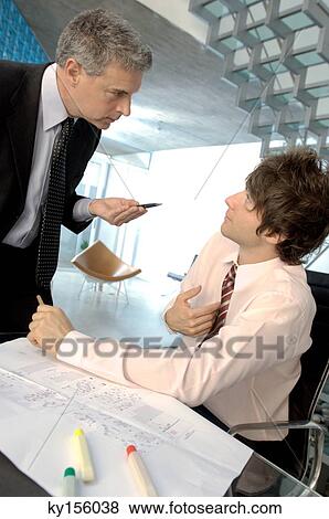 Businessman discussing with colleague in office View Large Photo Image Stock Photo - Businessman discussing with colleague in office. Fotosearch