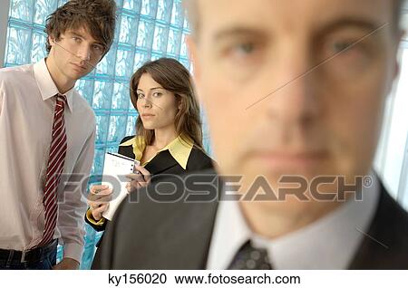 Businessman in office with colleagues in background View Large Photo Image Stock Image - Businessman in office with colleagues in background. Fotosearch