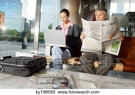 Businesswoman using laptop while businessman reading newspaper View Large Photo Image Stock Image - Businesswoman using laptop while businessman reading newspaper. Fotosearch